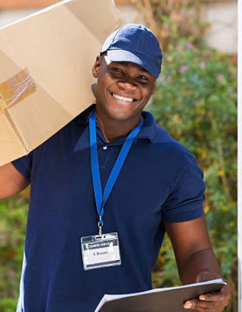 cheerful african courier standing with parcel at the door